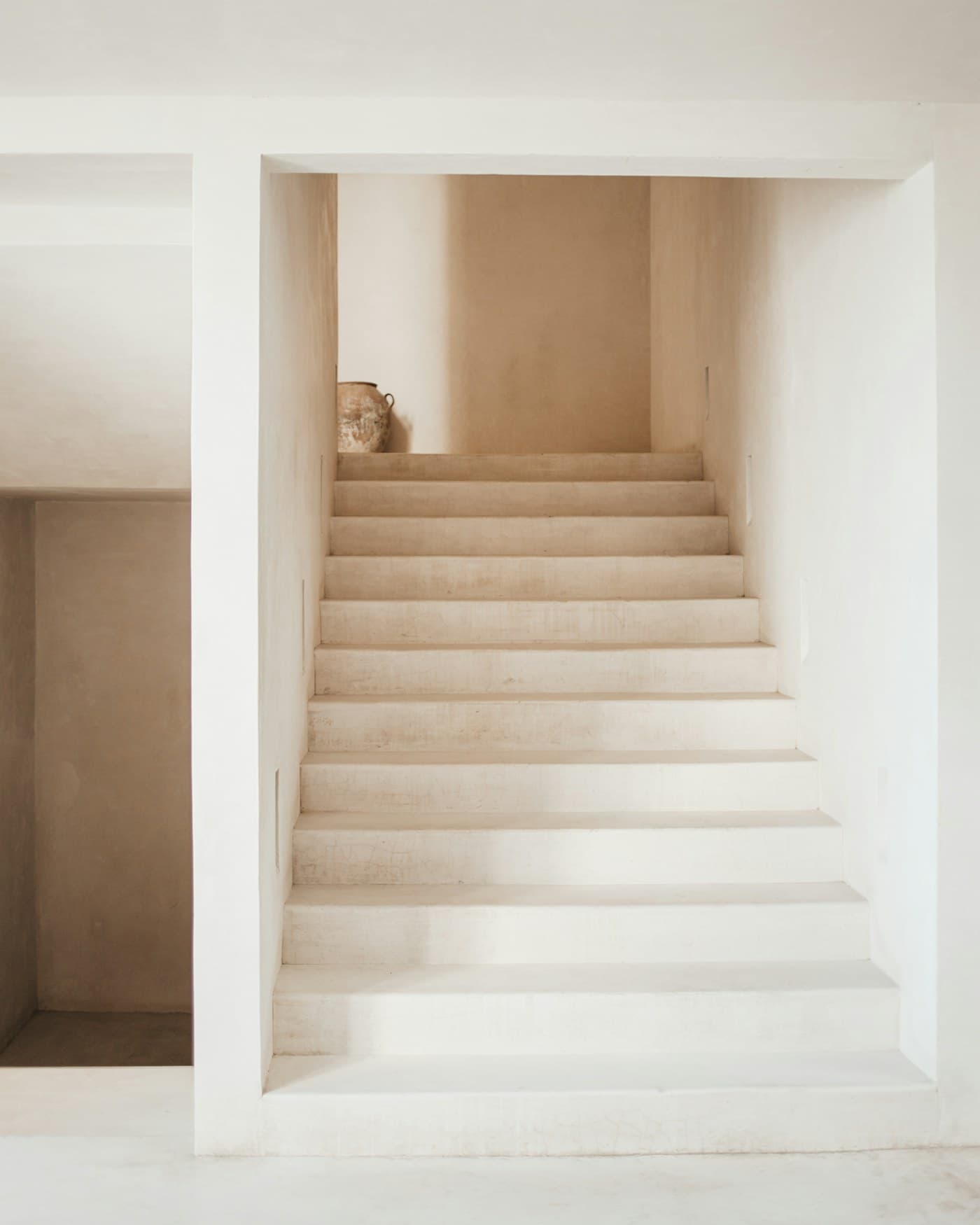 A pale stone staircase rising between two walls.