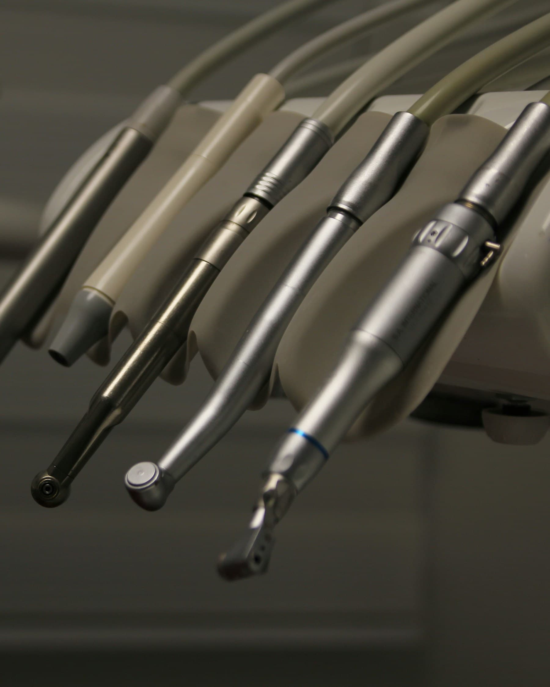 A row of dental instruments in low light.