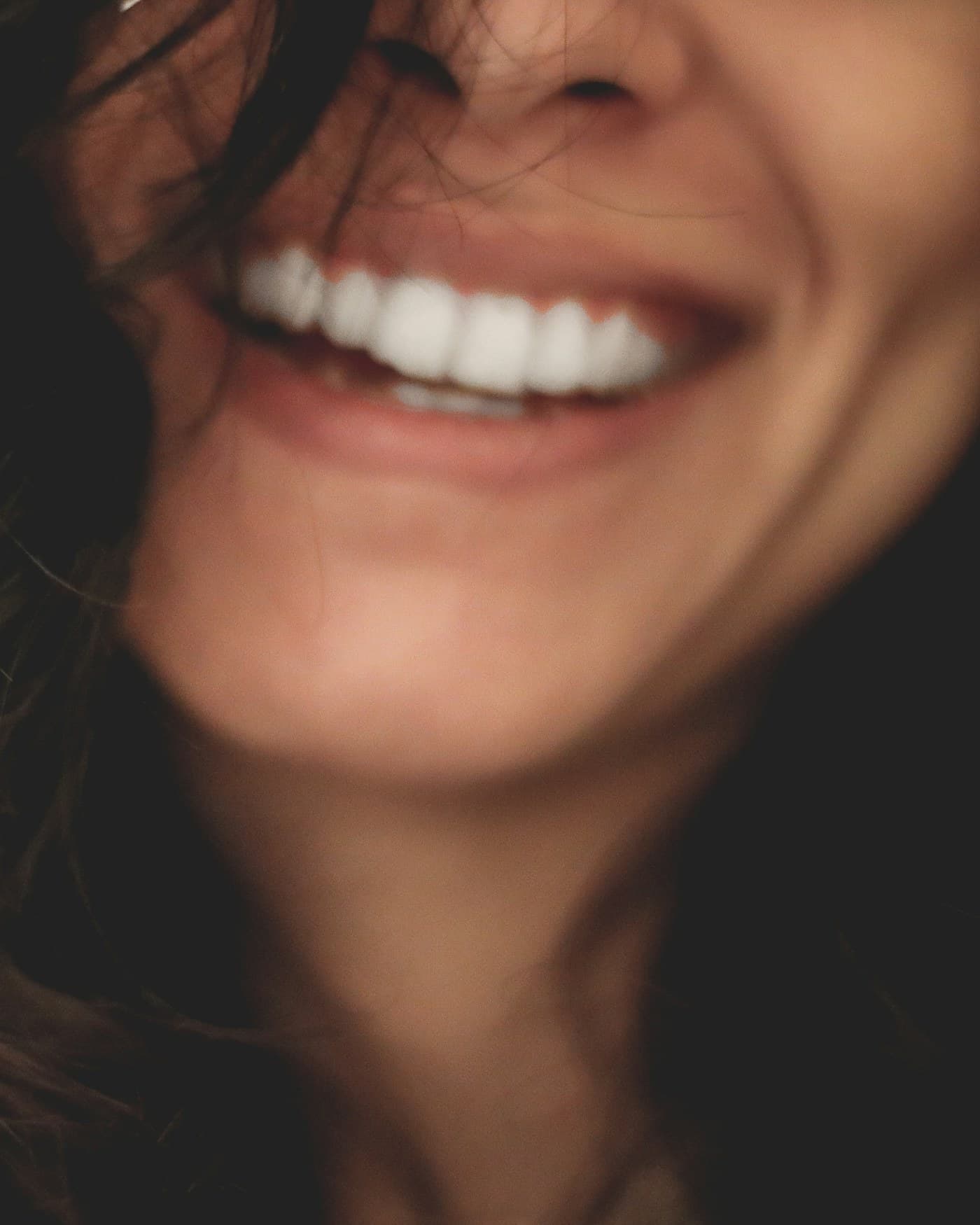 A woman smiling in soft daylight, photographed close.